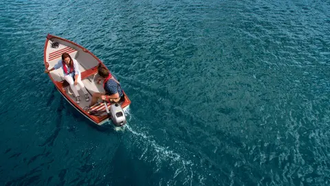 Couple sur un bateau avec moteur Honda sur l'eau.