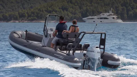 Couple sur un bateau Highfield orienté vers l’arrière équipé d'un moteur BF50 en bord de mer.