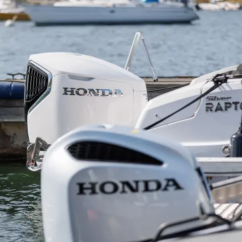 Gros plan sur des moteurs Honda à l’arrière de bateaux dans l’eau. 